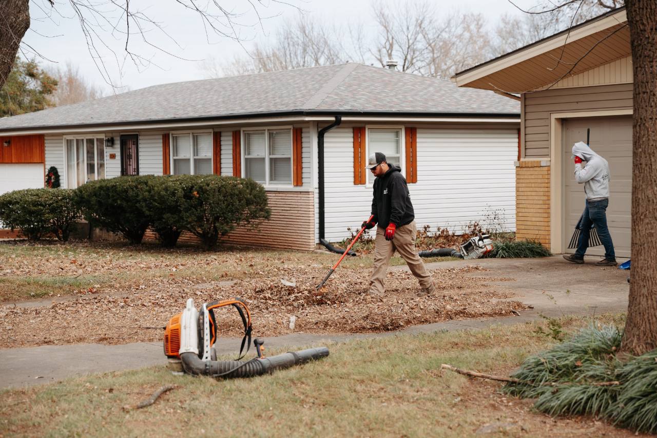 No Mow Worries crew clearing fallen leaves from a residential yard